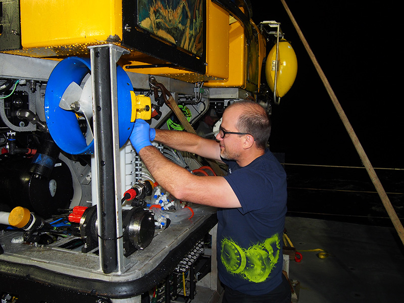 Senior Research Scientist John Burns making adjustments to a submersible on the deck of a ship