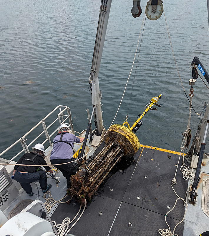 workers on the deck of the RV Bowditch attending to a remote sensing buoy